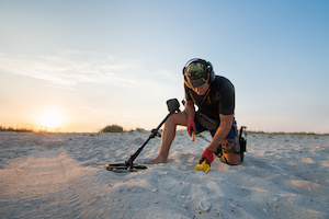 Man med en metalldetektor på en strand